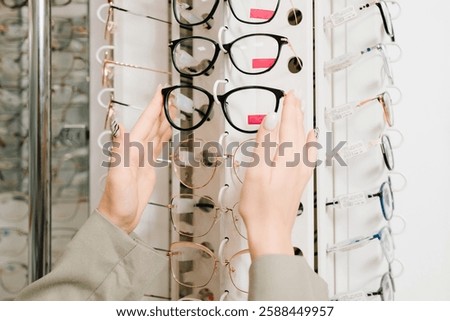 Selection of eyeglasses with different frames for vision care. Woman chooses eyeglasses with clear lenses in the optician store
