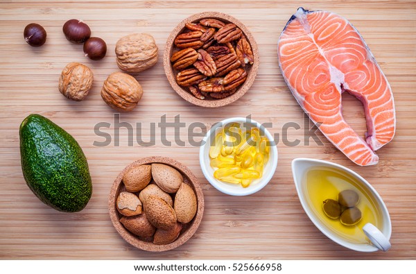 Selection food sources of omega 3 and unsaturated fats. Super food high vitamin e and dietary fiber for healthy food. Almond ,pecan ,hazelnuts,walnuts ,olive oil ,fish oil ,salmon  on cutting board.