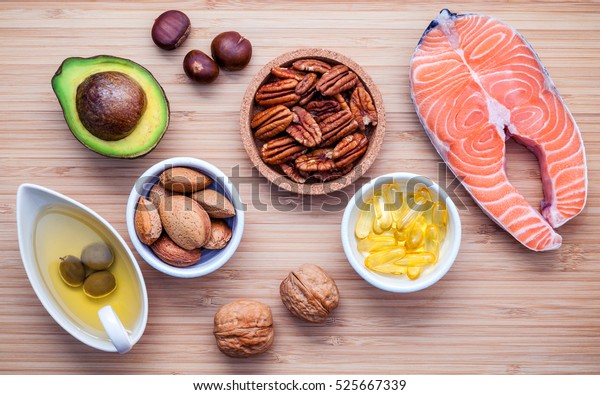 Selection food sources of omega 3 and unsaturated\
fats. Super food high vitamin e and dietary fiber for healthy food.\
Almond ,pecan ,hazelnuts,walnuts ,olive oil ,fish oil ,salmon  on\
cutting board.