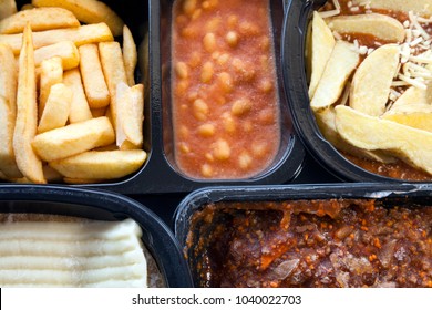 Selection Of Frozen, Processed, Ready Made Foods Consisting Of Potato Chips, Mince, And Lasagna In Black, Plastic Containers. Microwave Meals Ready To Heat Up.