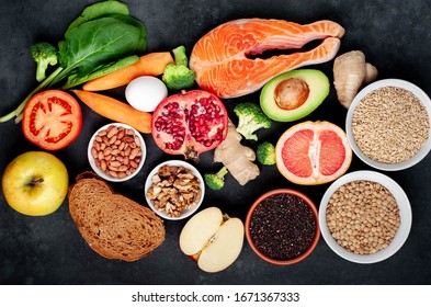 
 Selection of healthy food: salmon, fruits, seeds, cereals, superfoods, vegetables, leafy vegetables on a stone background. Healthy food for people.