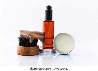 A selection of men's beard grooming products that include oil, wax and a brush, shot against a clean white background