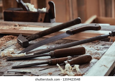 Selection of old vintage tools on a woodworking workbench with chisels, rasp, file, hammer and handsaw viewed low angle