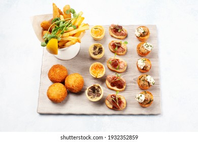 A Selection Of Canapés On A Board With Fries