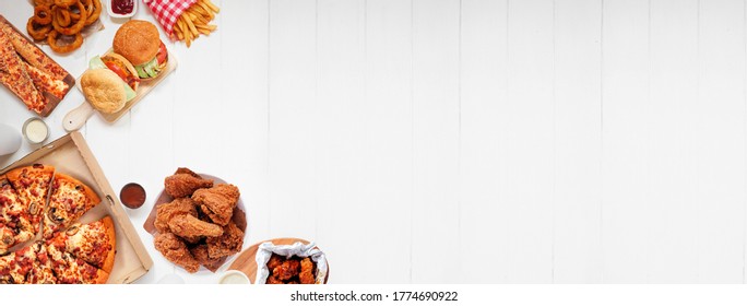 Selection of take out and fast foods. Corner border banner. Pizza, hamburgers, fried chicken and sides.  Top down view on a white wood background with copy space. - Powered by Shutterstock