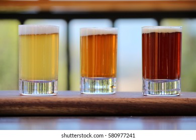 Selection Of Three Craft Beers On A Wooden Board During Beer Tasting