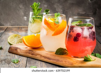 Selection of three kinds of gin tonic: with blackberries, with orange, with lime and mint leaves. In glasses on a rustic wooden background. Copy space  - Shutterstock ID 639702199