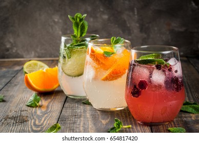 Selection of three kinds of gin tonic: with blackberries, with orange, with lime and mint leaves. In glasses on a rustic wooden background. Copy space  - Shutterstock ID 654817420