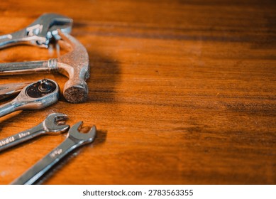 A selection of tools including a hammer and wrenches on a wooden surface.