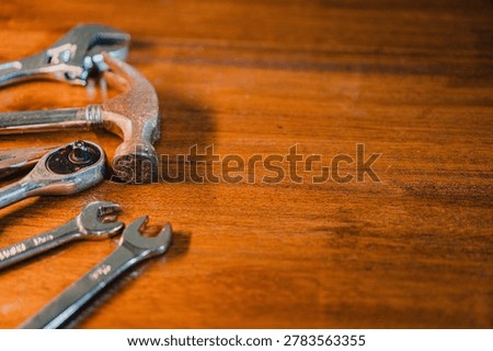 A selection of tools including a hammer and wrenches on a wooden surface.