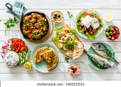 Selection Of Traditional Greek Food - Salad, Meze, Pie, Fish, Tzatziki, Dolma On Wood Background, Top View