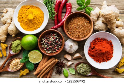 A selection of various colorful spices on a wooden table in bowls and spoons - Shutterstock ID 1925507492