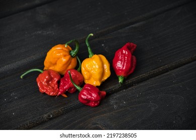 Selection of very hot peppers (Carolina Reaper, Scotch Bonnet, Habanero) on a black wooden table