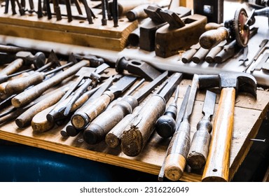 A selection of wood carving tools arranged neatly on a workbench in a woodworking shop - Powered by Shutterstock