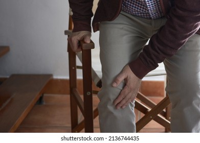 Selective Blur. Horizontal Photo With Copy Space On The Left. An Elderly Man Puts His Hand On His Right Knee Because It Hurts When Getting Up From A Chair.