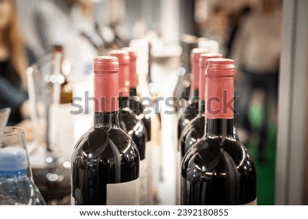 Selective blur on bottlenecks of bottles of red wine on display, ready for wine tasting, on a row, stacked in line.