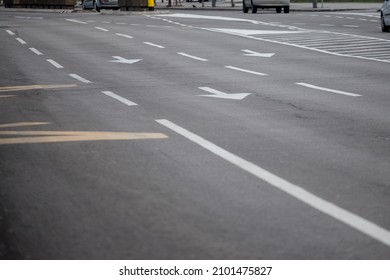 Selective blur on lane markings with painted directional arrows on thru lanes on asphalt, on a city urban road used for heavy traffic, in Europe, abiding by european standards. 