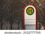 Selective blur on a typical austrian and german bus stop sign, called haltestelle, or bushaltestelle, in a dortmund urban environment. it indicates the presence of a public transportation stop station