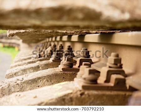 Selective field of focus. Detail of rusty screws and nut on old railroad track. Concrete tie with rusty nuts and bolts. Damaged surface of rail rod. No train passed this railroad for a long time.
