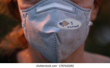 Selective focis on I Voted sticker with USA flag on face mask on caucasian female after voting for president for President