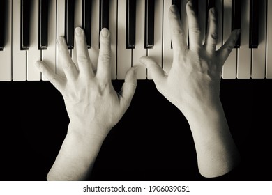 Selective focus from above on female hands playing the piano. Close-up, black isolated layer, copy space. Vintage tinting. The concept of home hobbies authentic