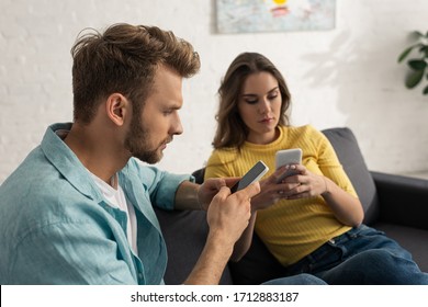 Selective focus of addicted couple using smartphones on couch