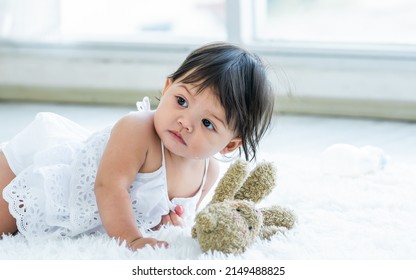 Selective Focus Adorable Caucasian Little Baby Daughter Girl, Smiling, Crawling On The Floor, Playing Alone In Comfortable Living Room At Home Or House With Happiness. Kid Development Concept