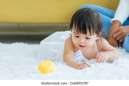 Selective Focus Adorable Caucasian Little Baby Daughter Girl, Smiling, Crawling On The Floor, Playing Alone In Comfortable Living Room At Home Or House With Happiness. Kid Development Concept