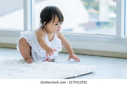 Selective Focus Adorable Caucasian Little Baby Daughter Girl, Smiling, Crawling On The Floor, Playing Alone In Comfortable Living Room At Home Or House With Happiness. Kid Development Concept