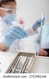 Selective Focus Of African American Dentist In Medical Mask And Face Shield Taking Stainless Dental Mirror