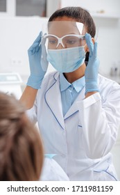 Selective Focus Of African American Dentist In Medical Mask Touching Face Shield Near Patient