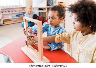 Selective Focus Of African American Kids Playing With Scores With Teacher And Child At Background In Montessori School