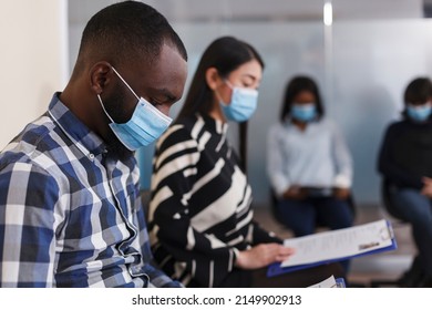 Selective Focus Of African American Man In Busines Company Waiting Room Reading Internal Regulations And Job Offer. Unemployed Job Candidate Sitting In Lobby Area While Waiting For HR Manager.