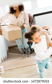 Selective Focus Of African American Mother Going Upstairs While Kid Holding Teddy Bear 