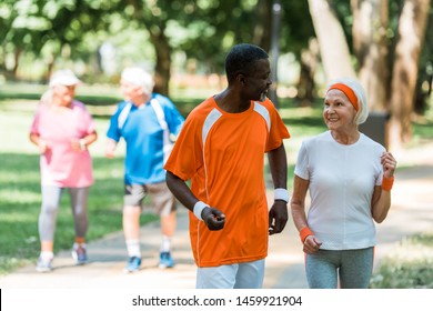 selective focus of african american senior man and cheerful retired woman exercising near pensioners outside  - Powered by Shutterstock