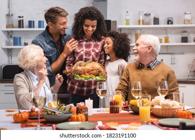 Selective focus of african american woman holding turkey near family during thanksgiving celebration - Powered by Shutterstock