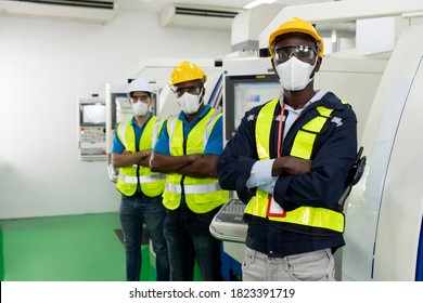Selective focus of African American worker. Multiethnic engineer standing arms crossed and wearing surgical mask to prevent covid-19 in manufacturing factory. Concept of race equality in workplace. - Shutterstock ID 1823391719