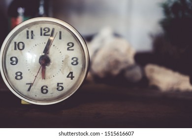 Selective Focus Of Alarm Clock On Side Table Beside Bed Show 6 O'clock In The Morning Background.Time In Life Early Bird Person Productive Concept.