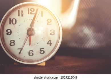 Selective Focus Of Alarm Clock On Side Table Beside Bed Show 6 O'clock In The Morning Background.Time In Life Early Bird Person Productive Concept.