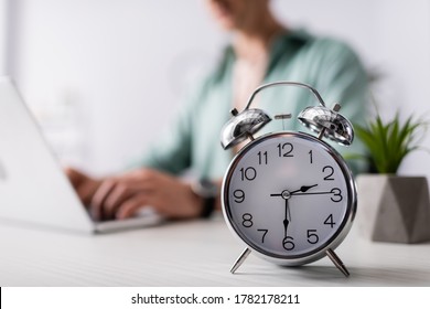 Selective focus of alarm clock on table near man using laptop at home, concept of time management - Shutterstock ID 1782178211