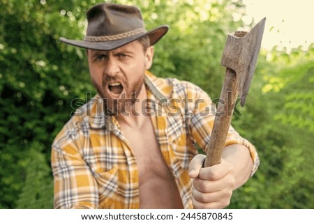 selective focus of angry lumberjack with axe. angry lumberjack with axe wearing checkered shirt