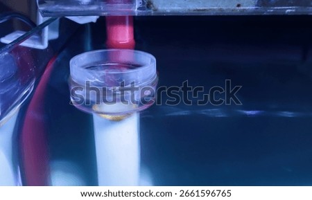 Selective focus of an aquarium surface skimmer submerged in water. The transparent plastic device removes debris and organic film from the water surface, keeping the aquarium clean and clear.