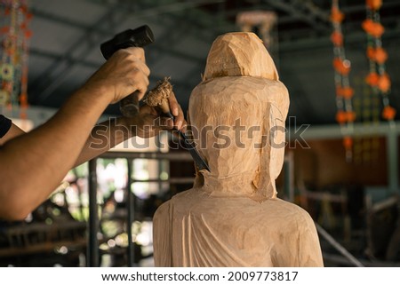 Selective focus. Asia craftsman professional carving buddha statue with chisel in workshop. Artist engrave wood. Carpentry woodwork. Handcraft carved.