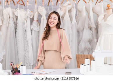 Selective focus Asian confident female smile designer wedding fashion. Woman SME start up small business wedding store. Young woman entrepreneur designer creative textile with sewing machine in store.