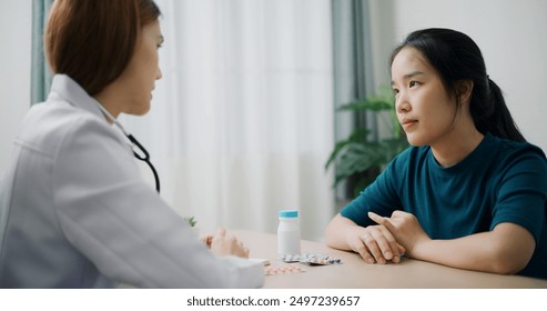 Selective focus, Asian doctor explaining how to take medicine to young female patient in clinic office, Health and medicine consultant, Conversation about healthcare
