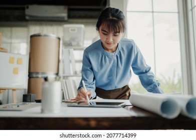 Selective focus, Asian female architect or engineer Drawing the design of the building's interior using a tablet. Asian female architect or engineer Sit and analyze, design projects in the office.