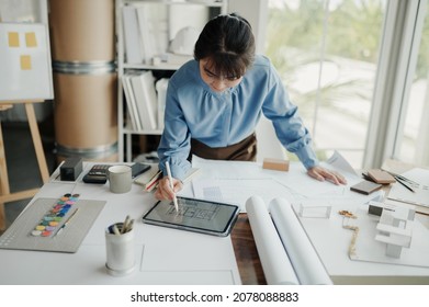 Selective focus, Asian female architect or engineer Drawing the design of the building's interior using a tablet. Asian female architect or engineer Sit and analyze, design projects in the office.