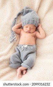 Selective Focus Of Asian Little Baby Sleeping On Back With His Hands Behind His Head On Beige Blanket, Adorable Toddler Wearing Knitted Gray Hat. Infant Sleeping On Bed With Happy And Safe.