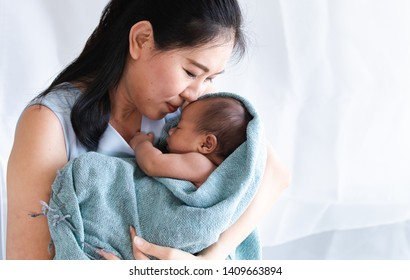 Selective focus Asian  mother bonding kissing newborn 0-1 month birth gently soft with love, little infant parcel, wrap with blanket feeling comfortable, secure in mother arm, mom nursing baby at home