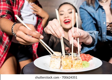 selective focus of asian woman eating sushi with friends
